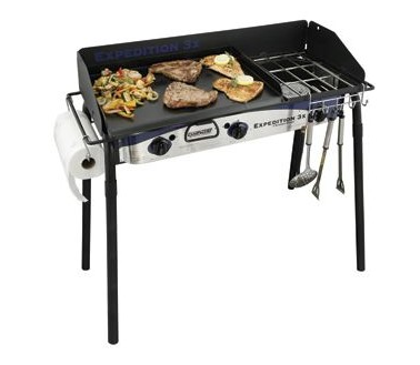 Portable gas grill with food cooking on the griddle.