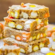 A stack of candy-filled blondies on a wooden surface.