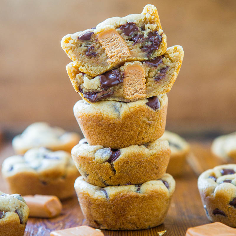 A stack of chocolate chip cookies with visible chunks of chocolate and cookie dough on a wooden surface.