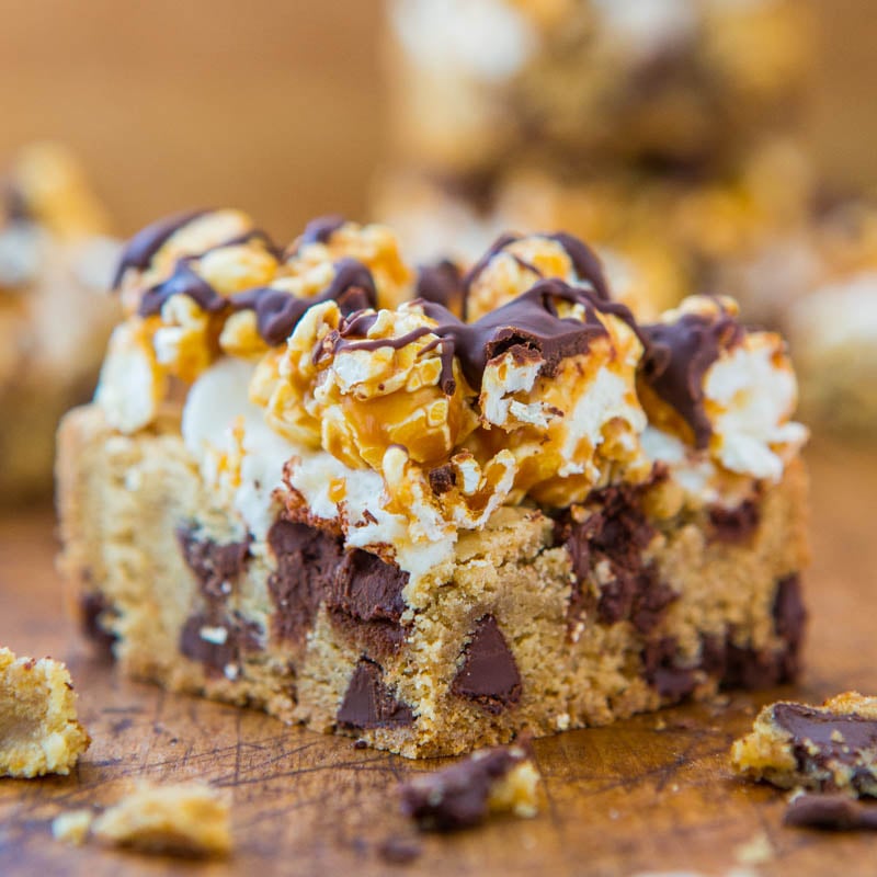 A close-up of a dessert bar with a cookie base, chocolate chunks, marshmallows, and drizzled chocolate topping.