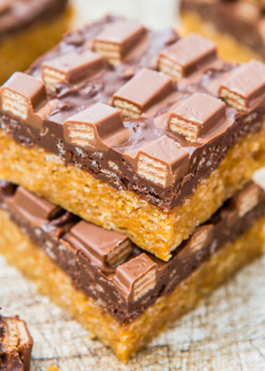 Stack of chocolate caramel slices on a textured surface.