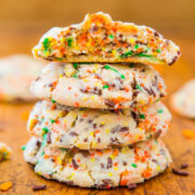 A stack of colorful sprinkle cookies with one cookie on top bitten in half.