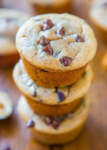 A stack of freshly baked chocolate chip cookies on a wooden surface.