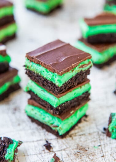 A stack of mint chocolate layered dessert bars on a surface.