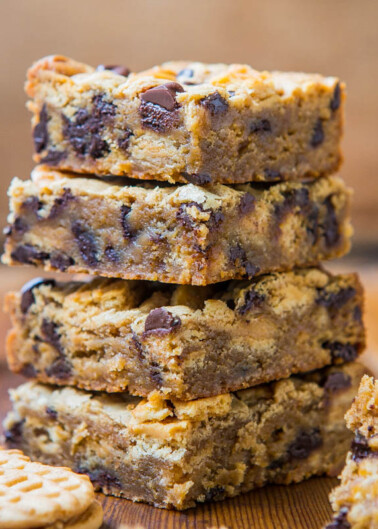 A stack of chocolate chip cookie bars on a wooden surface.