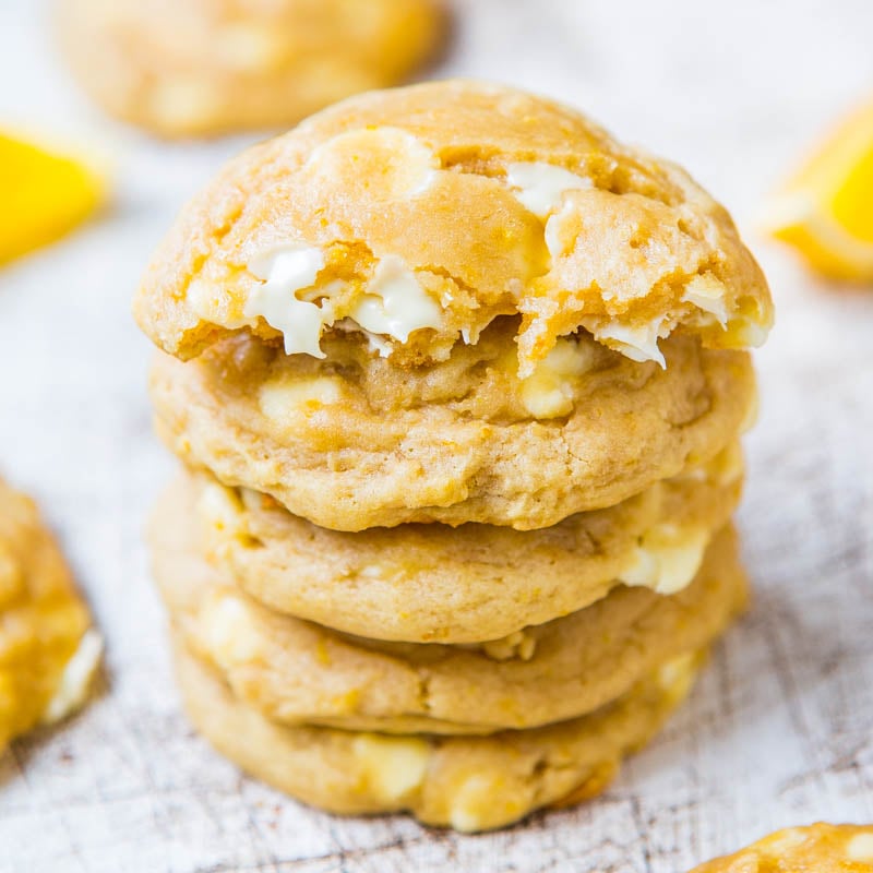 A stack of lemon-flavored cookies with white icing on a wooden surface.