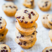 A stack of chocolate chip mini muffins on a textured surface.