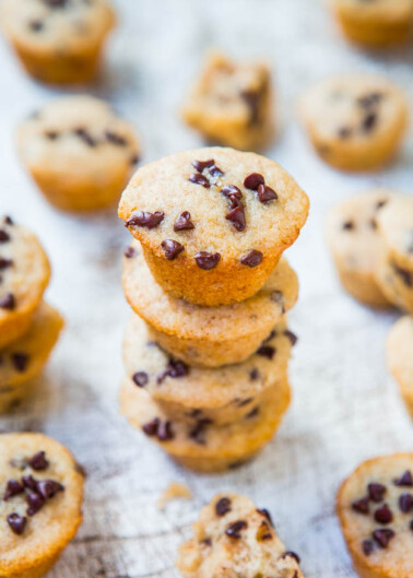 A stack of chocolate chip mini muffins on a textured surface.