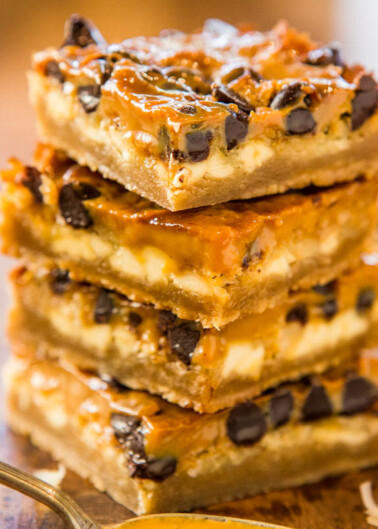 A stack of caramel and chocolate chip squares on a wooden surface.
