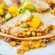 Vegetable quesadilla with corn, beans, peppers, and avocado on a white plate.