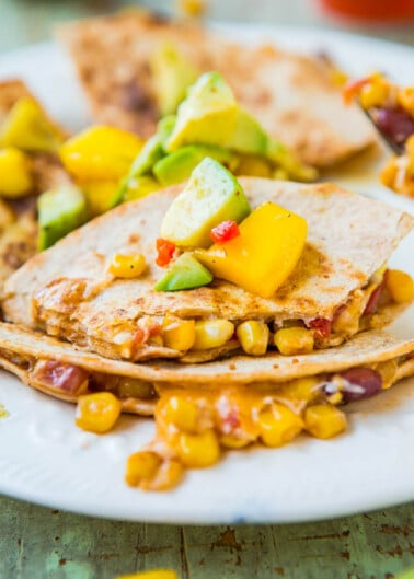 Vegetable quesadilla with corn, beans, peppers, and avocado on a white plate.