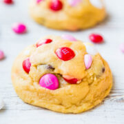 Freshly baked cookies with pink and red candy pieces on a wooden surface.