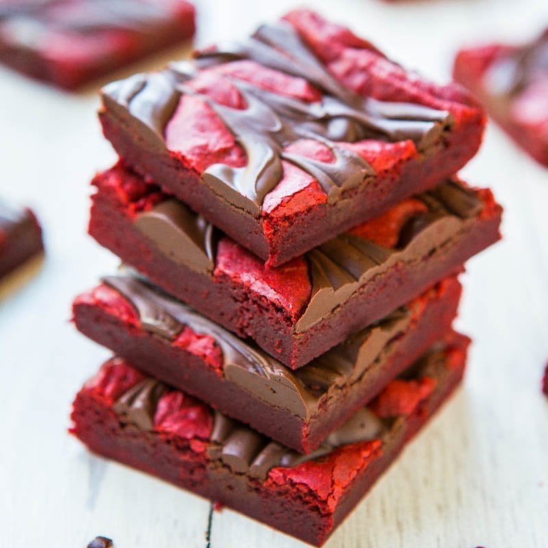 A stack of red velvet brownies with a drizzle of chocolate on top.
