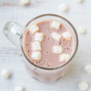 A mug of hot chocolate with marshmallows on a wooden surface.