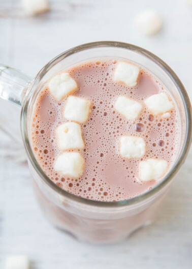 A mug of hot chocolate with marshmallows on a wooden surface.