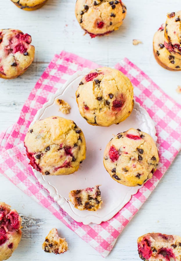 chocolate chip strawberry muffins on white plate with other muffins scattered around