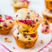 A stack of homemade mixed berry muffins on a white plate with a pink checkered napkin.