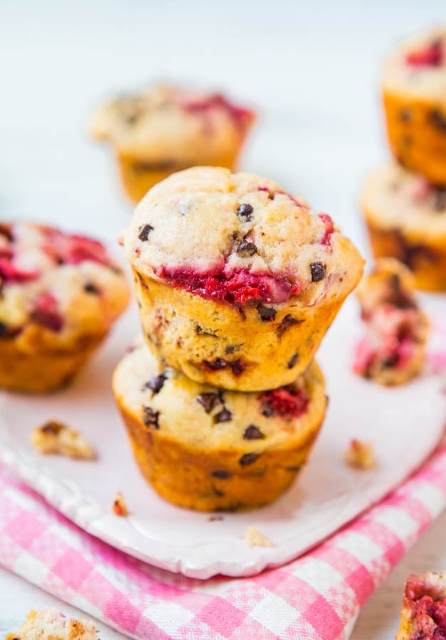 stack of two chocolate chip strawberry muffins on tea towel with other muffins