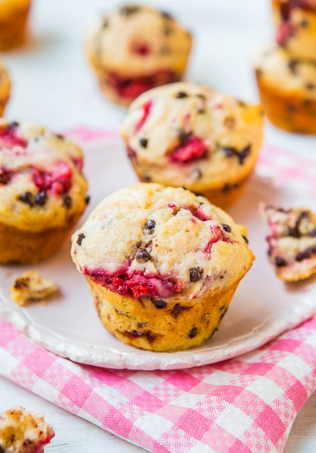 three chocolate chip strawberry muffins on white plate on tea towel