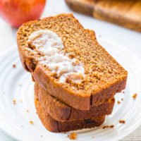 Two slices of pumpkin bread with a dollop of butter on a white plate.