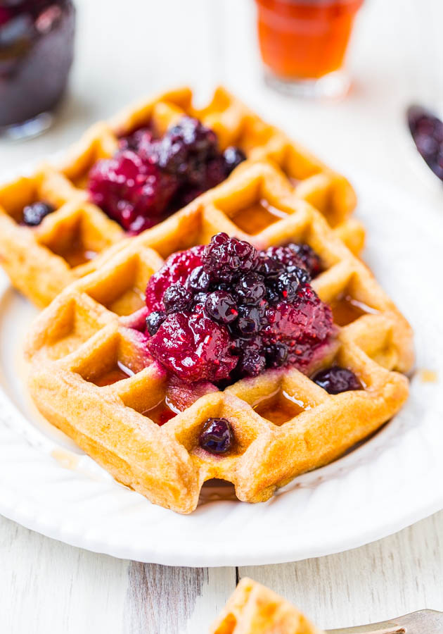 close up of two buttermilk waffles topped with berry preserves on a white plate