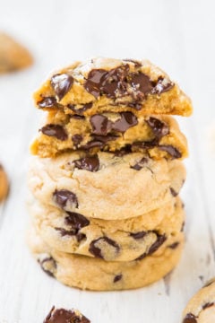 A stack of chocolate chip cookies with melted chocolate on a white surface.
