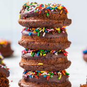 A stack of chocolate frosted donuts with colorful sprinkles.