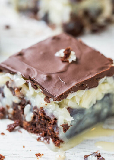 A close-up of a nanaimo bar, showing its layers of chocolate ganache, custard-flavored butter icing, and crumbly coconut-graham base.