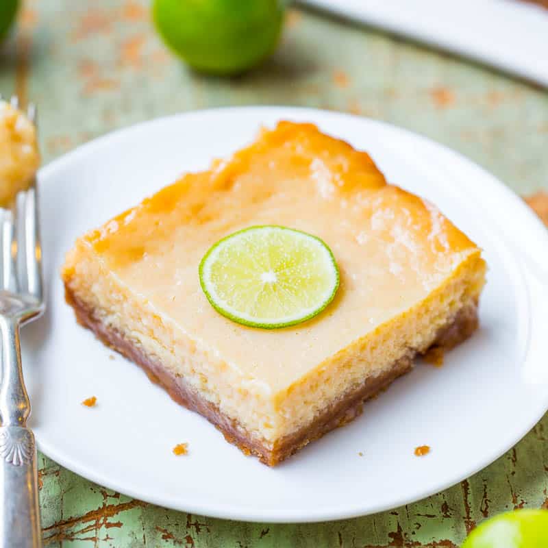 A slice of key lime pie with a lime garnish on a white plate.