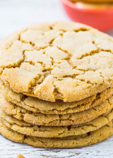 A stack of golden-brown peanut butter cookies on a wooden surface.