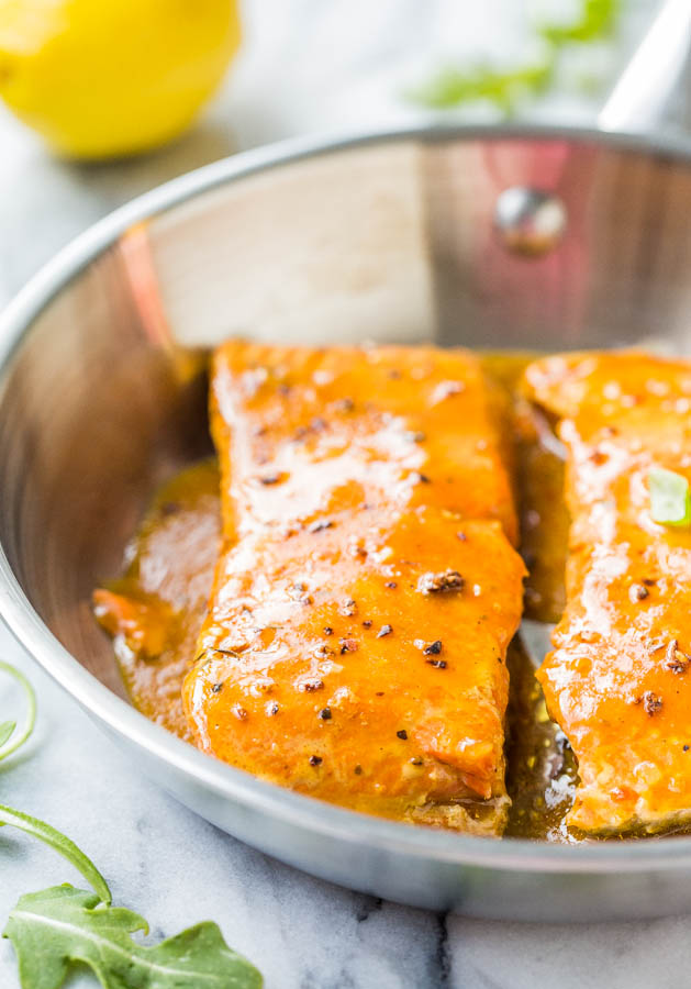 side view of two bbq sauce salmon fillets in a metal skillet 
