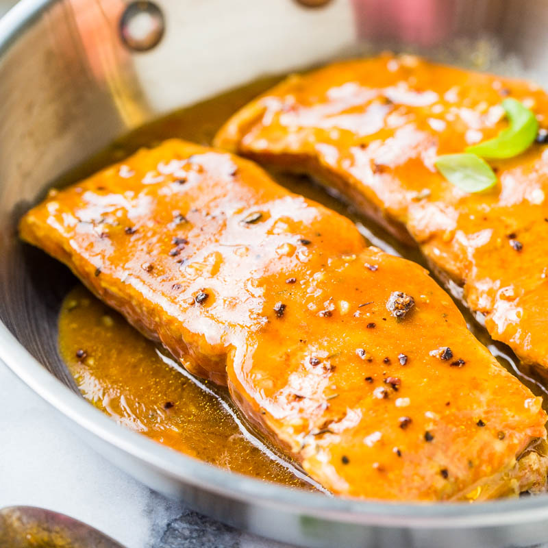 Two glazed salmon fillets in a pan.