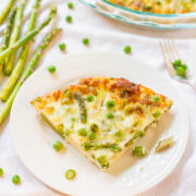 A slice of asparagus and pea quiche served on a white plate with whole asparagus on the side.