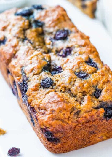 A freshly baked blueberry loaf on a white surface.