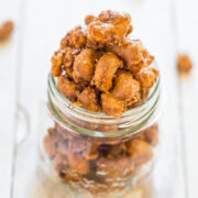 A jar of candied nuts on a reflective surface.