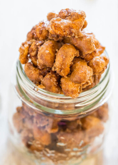 A jar of candied nuts on a reflective surface.