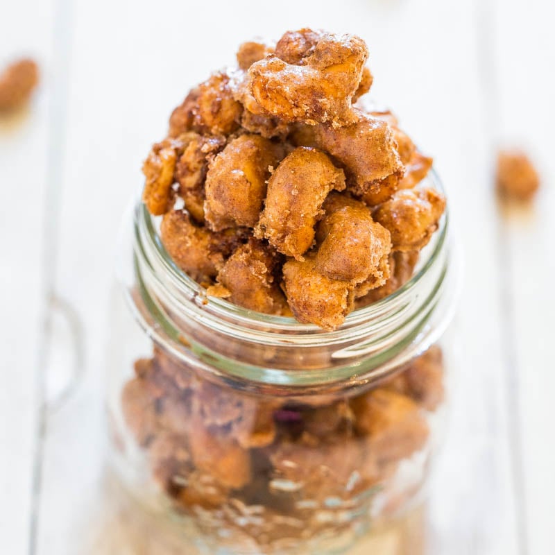 A jar of candied nuts on a reflective surface.