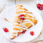 A fresh pastry with icing and fruit preserves on a decorative plate.