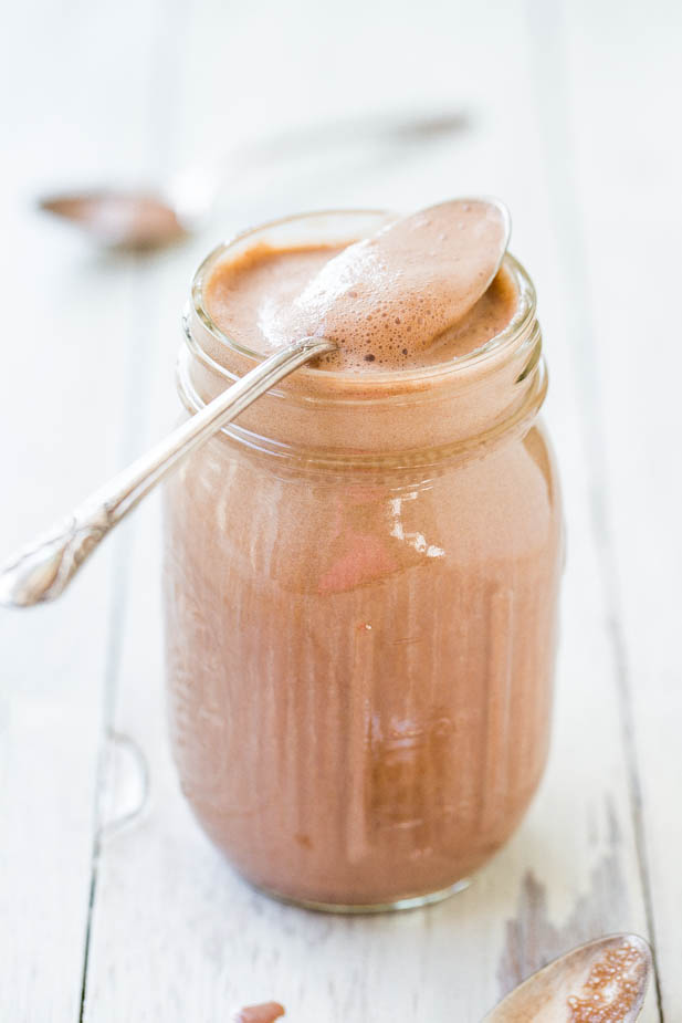 A jar of creamy chocolate spread with a spoon resting on top.
