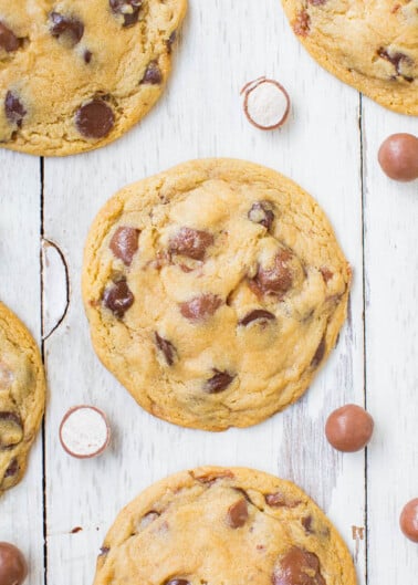 Freshly baked chocolate chip cookies with scattered candies on a wooden surface.