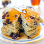 A stack of blueberry pancakes with syrup on a plate.