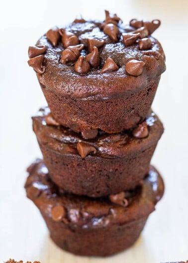 Three chocolate muffins stacked with chocolate chips on top.