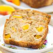 Sliced banana bread with peach pieces on a floral plate.