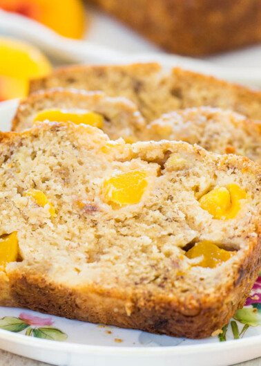 Sliced banana bread with peach pieces on a floral plate.