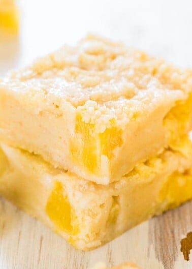 Two stacked lemon bars on a wooden surface.