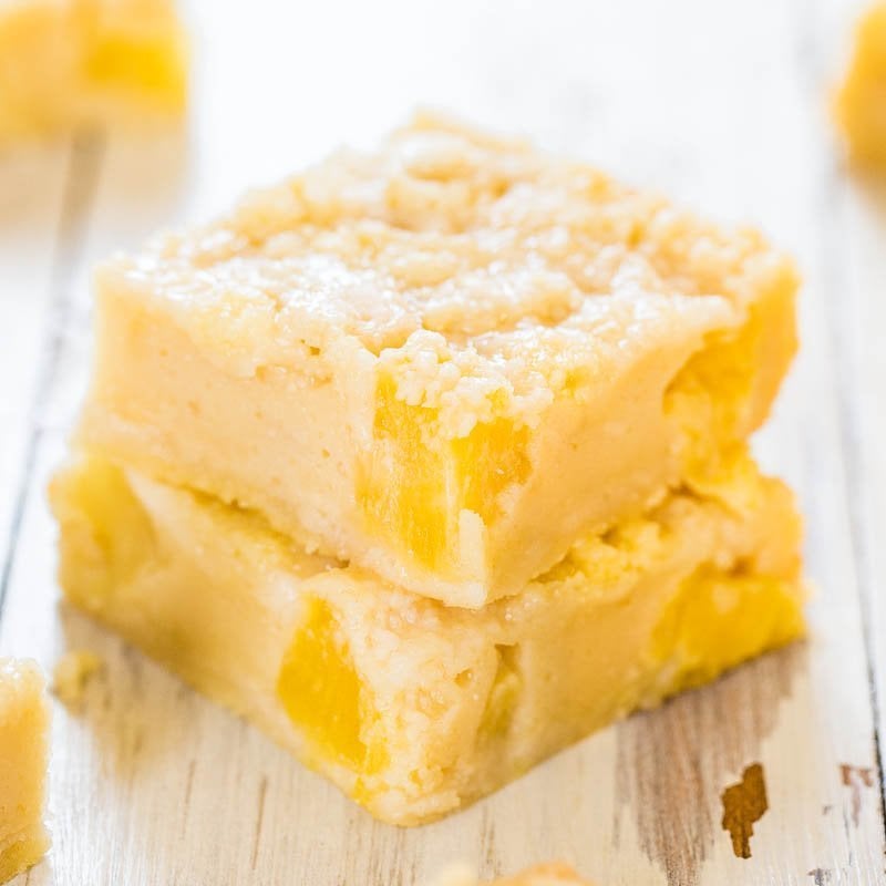 Two stacked lemon bars on a wooden surface.