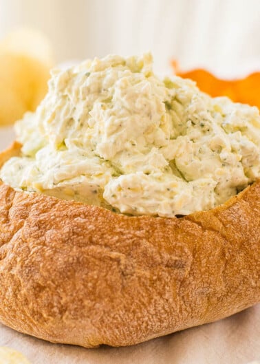 Bread bowl filled with creamy chicken salad on a table.