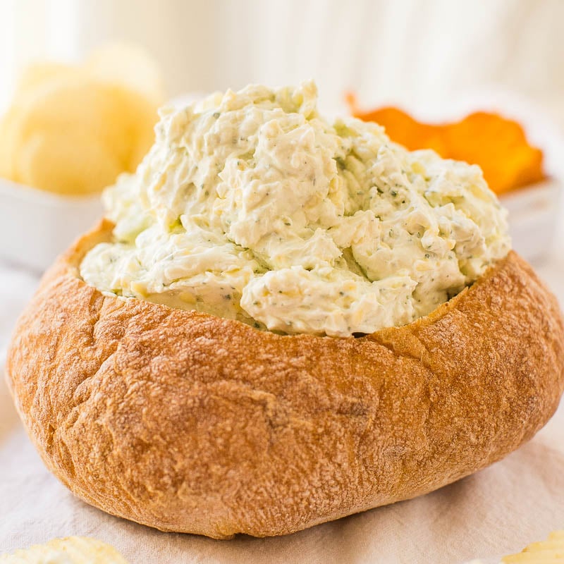 Bread bowl filled with creamy chicken salad on a table.