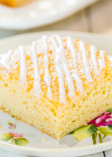 A slice of lemon drizzle cake on a floral plate.