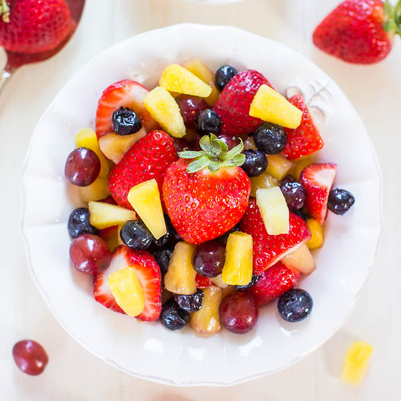 A bowl of fresh fruit salad containing strawberries, blueberries, grapes, and diced mango.